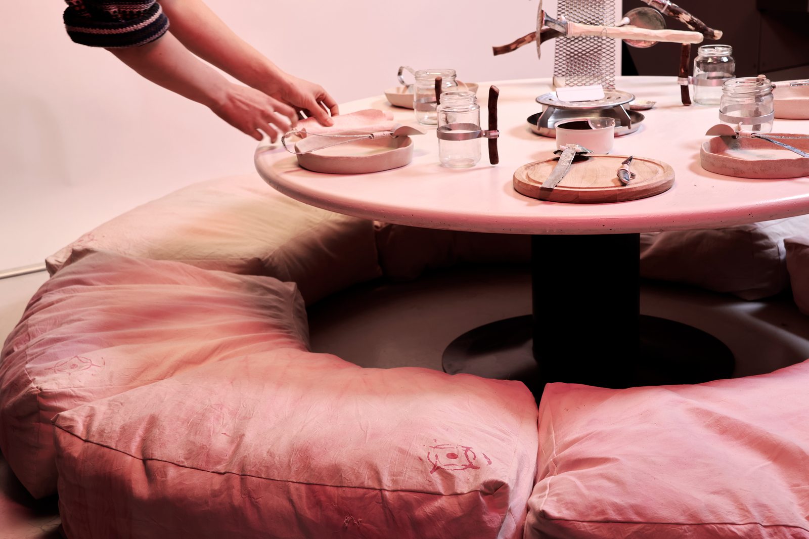 Aufbau des Tischgedecks mit skulpturalem Besteck auf dem rosa Tisch